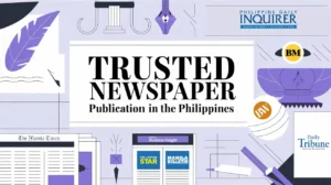 A newsroom with journalists working on computers and reviewing print materials, featuring a stack of newspapers and a digital screen, representing a top newspaper publication.